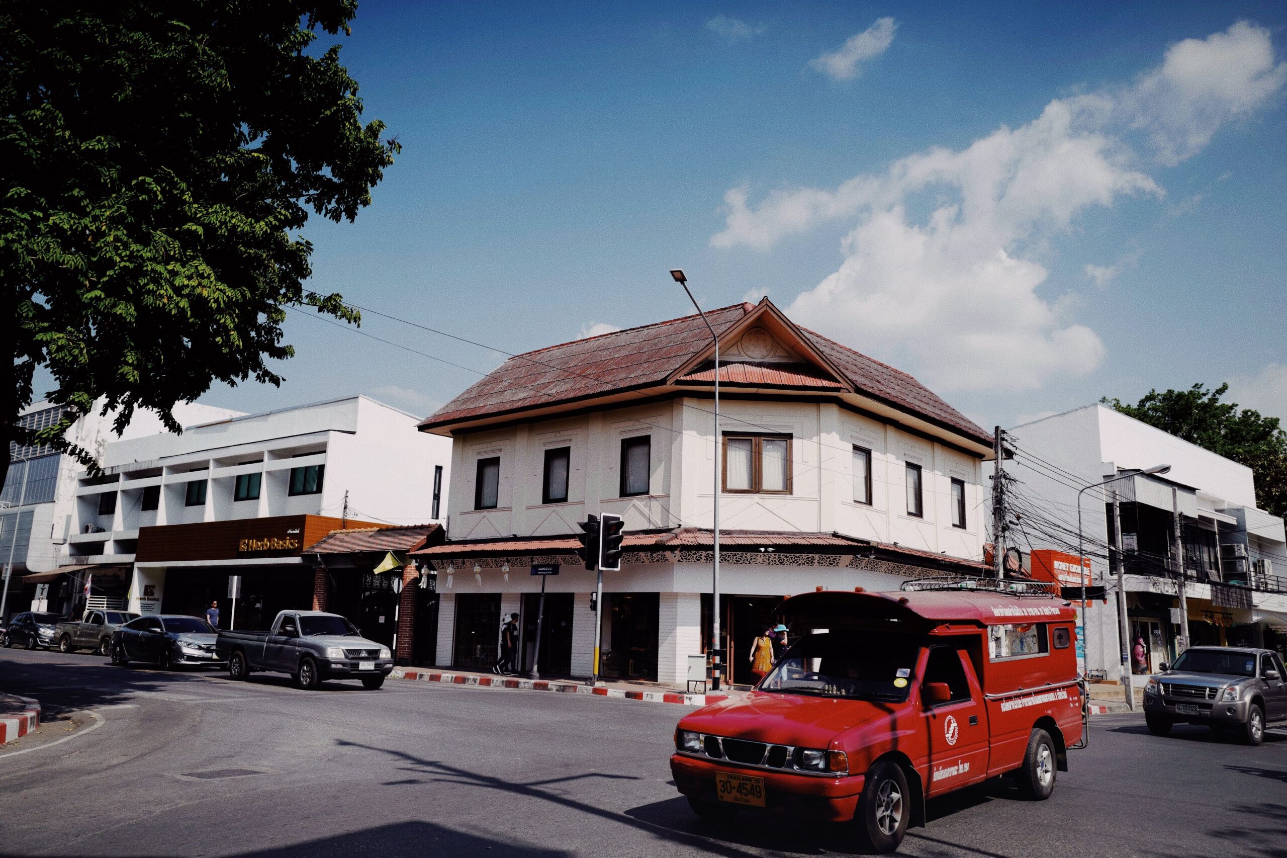 Red songthaew truck driving through a historic Chiang Mai street